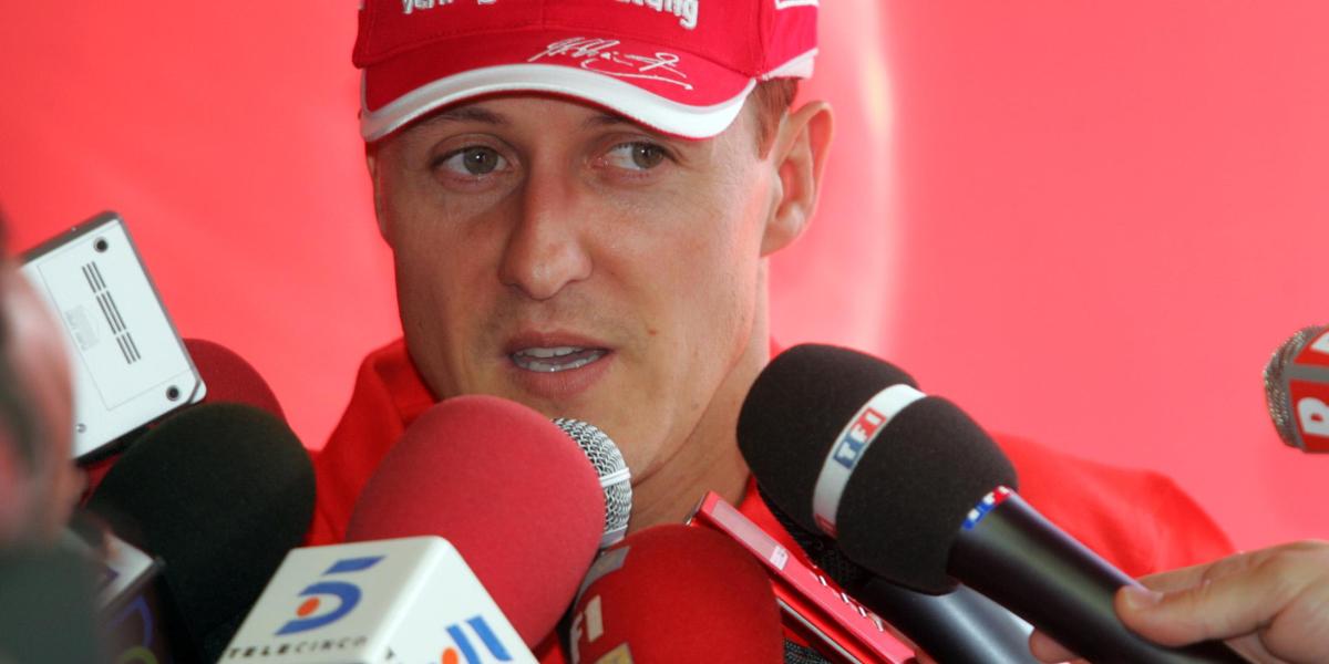 Michael Schumacher, con ayuda de su mujer, firma un casco para una causa benéfica